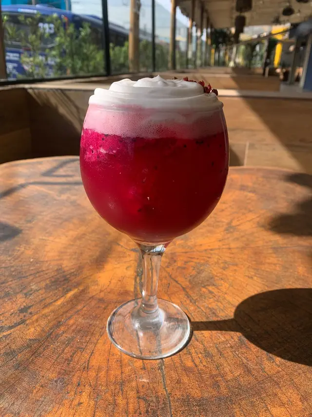 Drink roxo com espuma na mesa de madeira